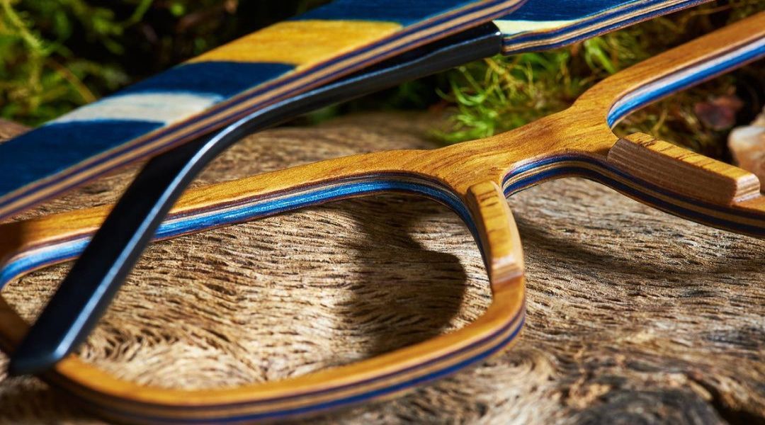A pair of wooden glasses sitting on top of a piece of wood .