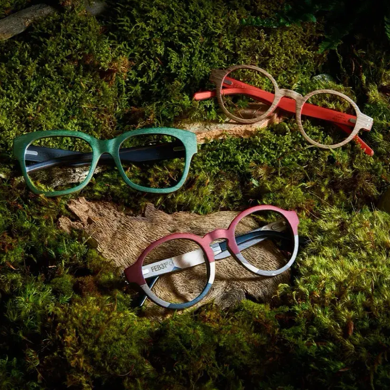 Three pairs of FEB31ST glasses are sitting on top of wood and moss.