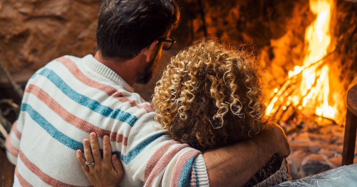 A man and a woman are sitting in front of a fire.