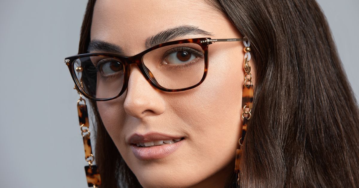 A close up of a woman wearing glasses with a neck chain attached.