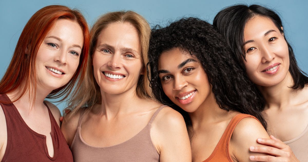 A group of four women are posing for a picture together and smiling.