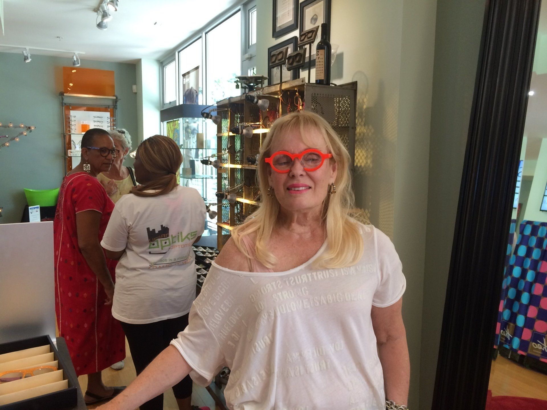 Woman in white blouse modeling colorful glasses at Theo Trunk Show event