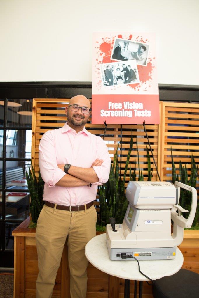 Person standing next to table set up for vision screening tests at 2018 Raise Your Glasses