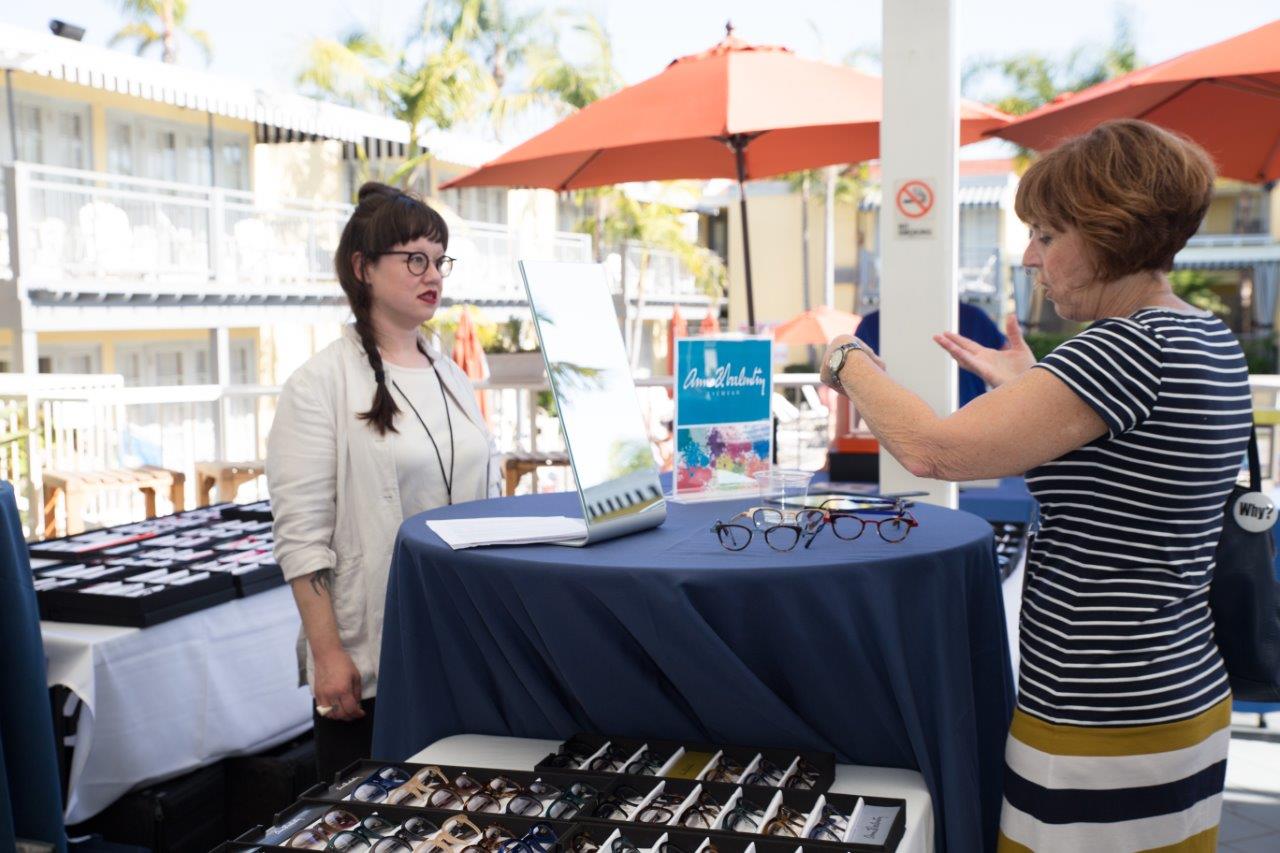 Vendor standing behind her tabletop display chatting with attendee  at Raise Your Glasses 2018 Event