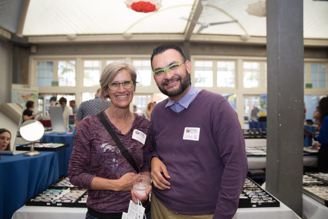 Two people wearing colorful glasses and smiling during Raise Your Glasses 2018 Event