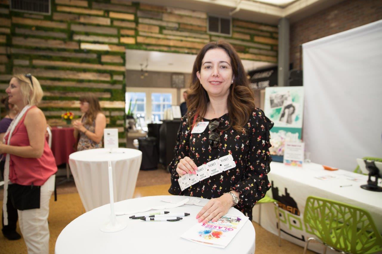 Woman standing indoors at table during Raise Your Glasses 2018 Event