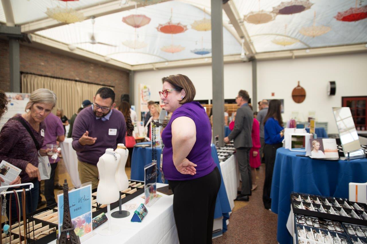 Vendor standing behind tabletop display at Raise Your Glasses 2018 Event