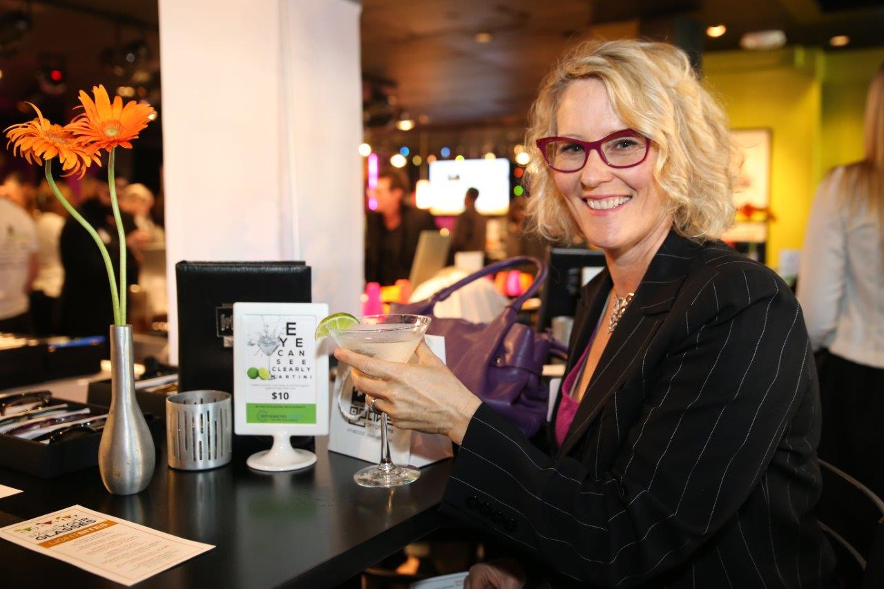 Woman smiling and holding martini at Raise Your Glasses event