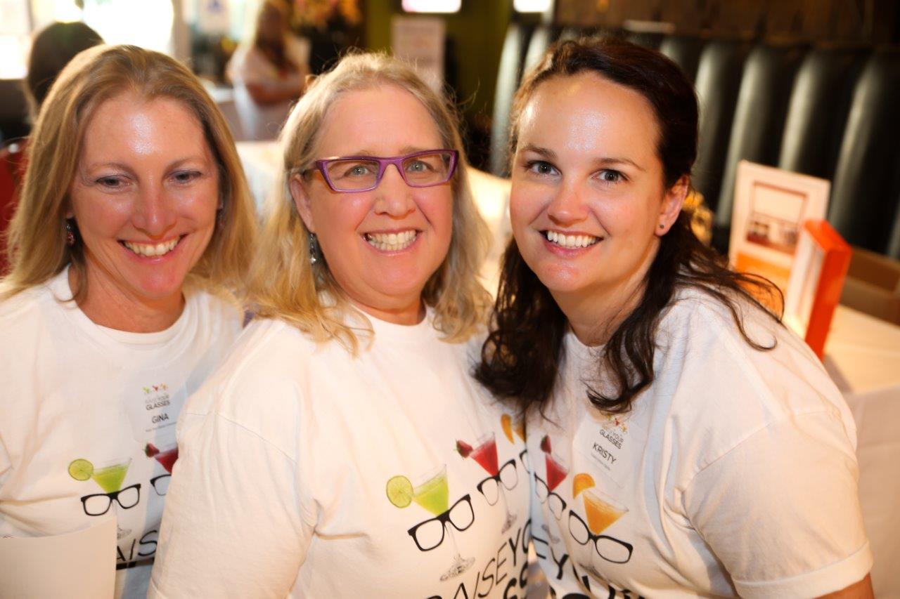 3 smiling staff members wearing event t-shirts