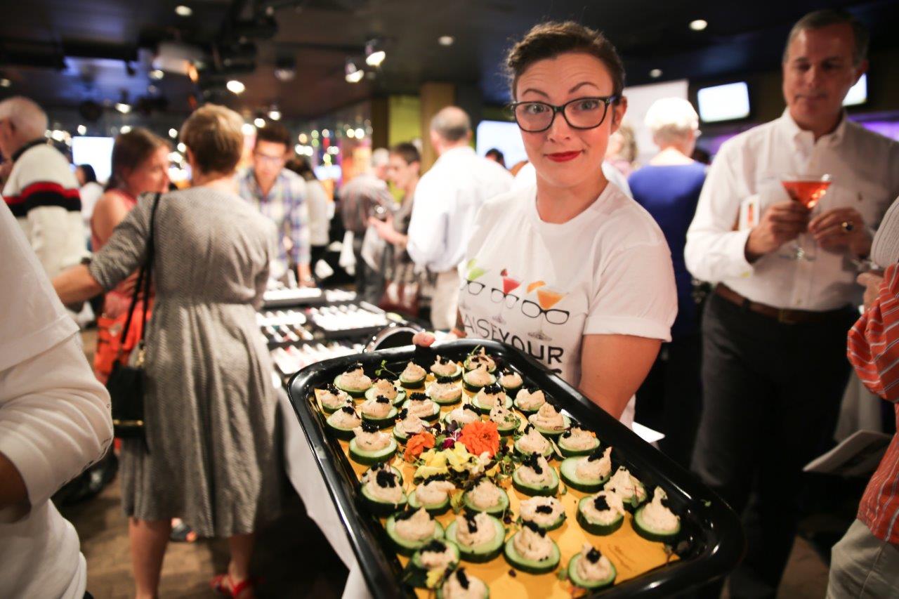 Person standing next to tray of food at Martinis Above Fourth at Raise Your Glasses event