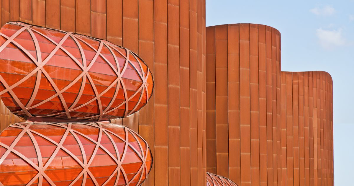 A row of red brick and geometric steel modern buildings with a blue sky in the background.