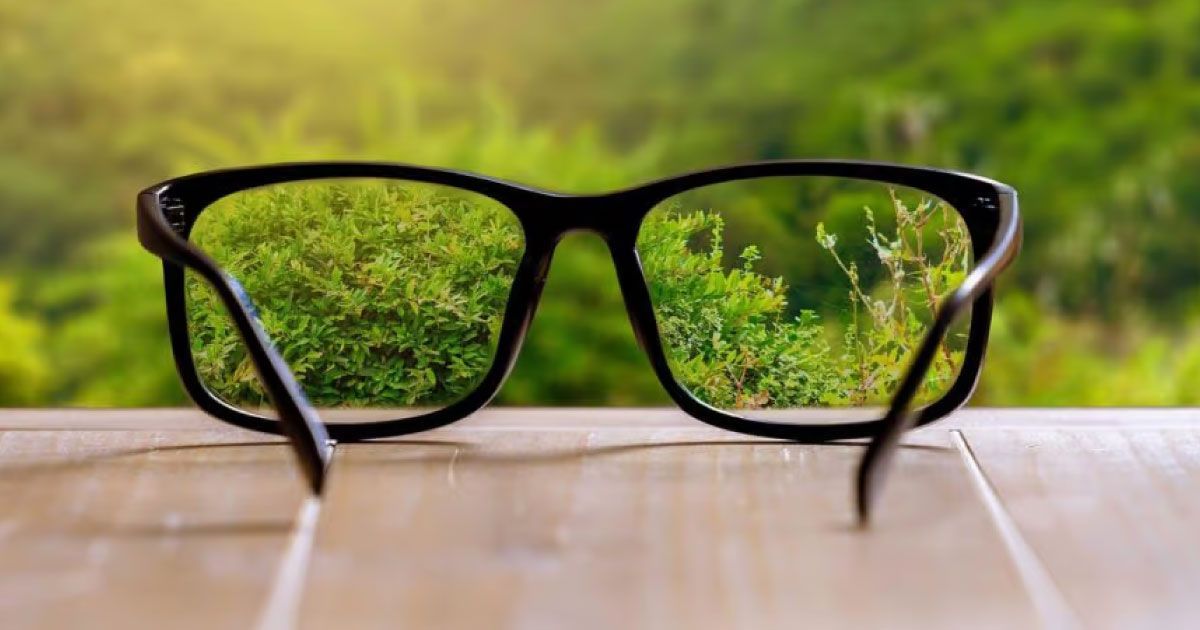 A pair of glasses sitting on a table showing a blurred background clear through the lenses