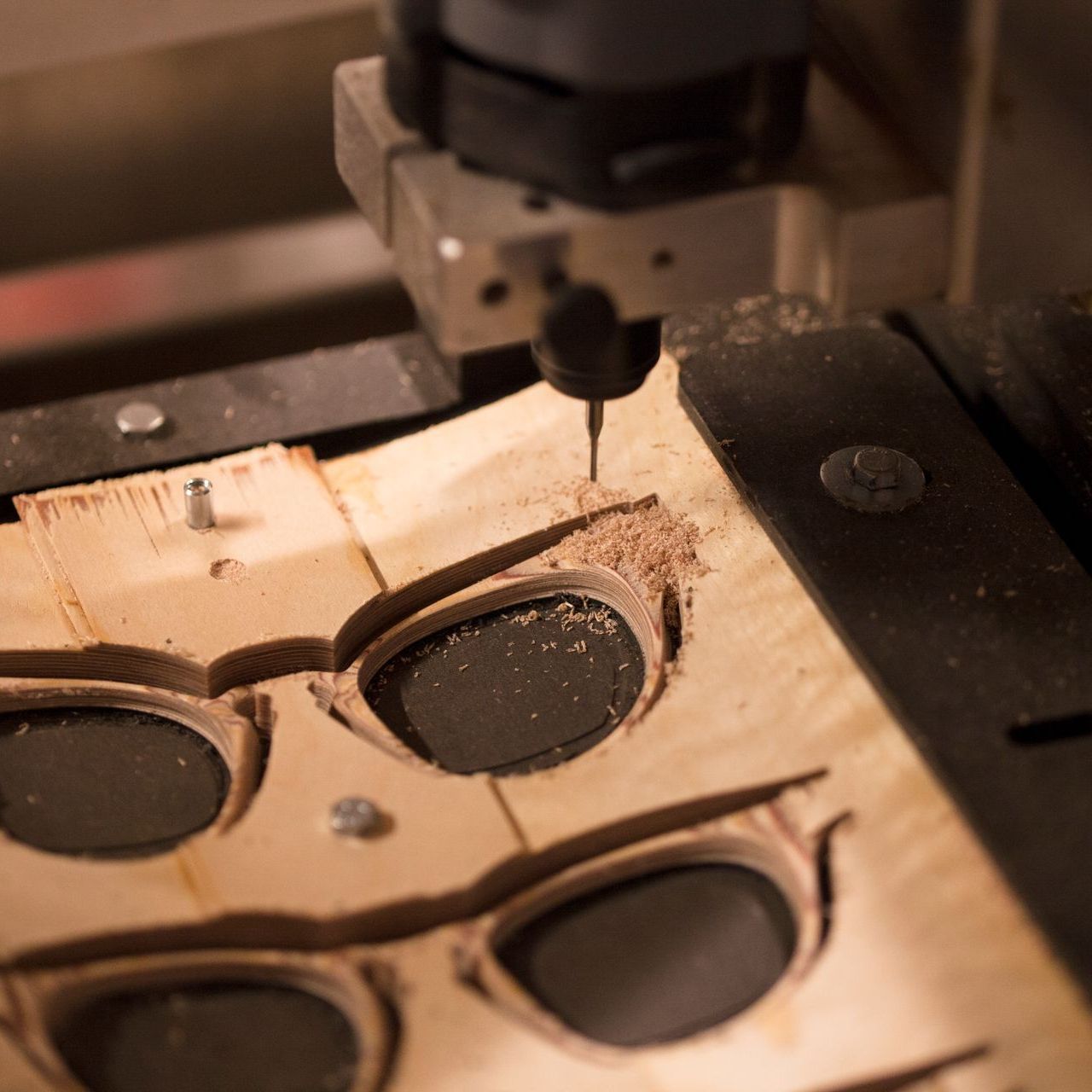 A machine is making a pair of glasses out of wood