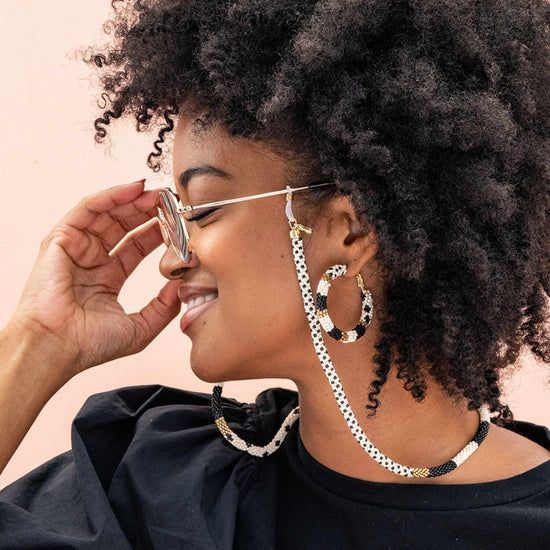 A woman wearing a pair of glasses with a black and white eyeglass chain