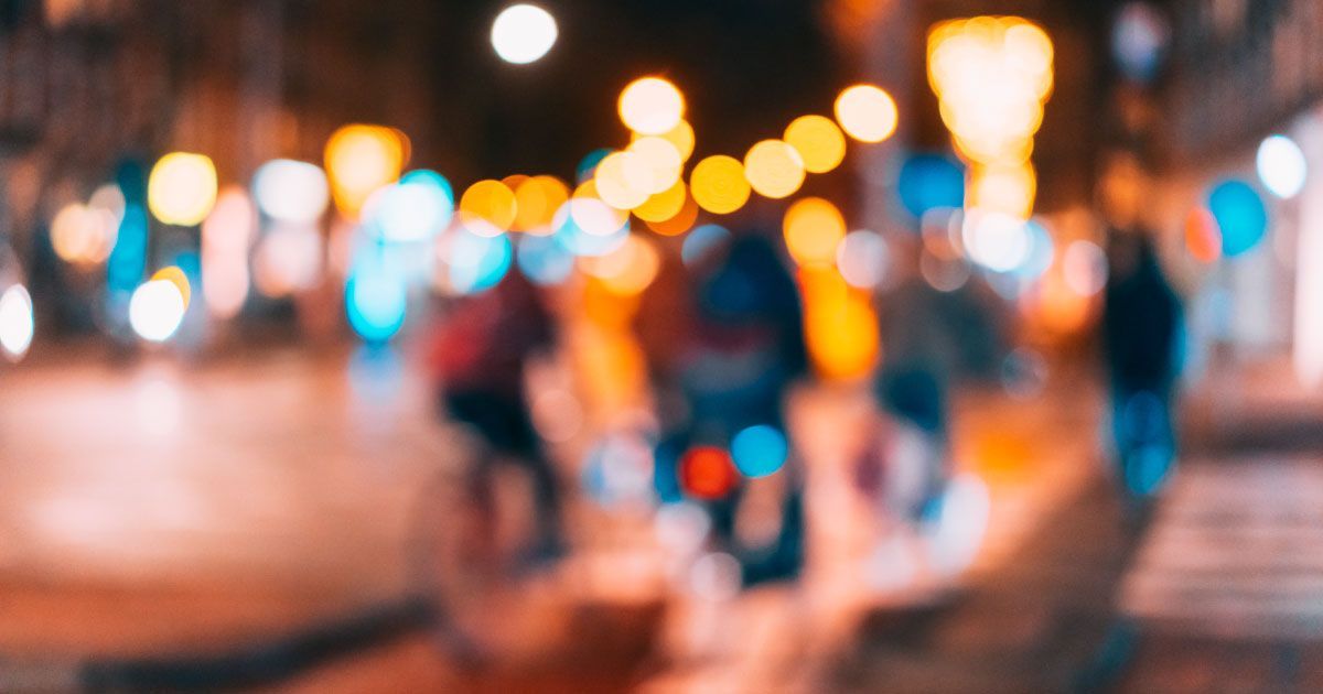 A blurry picture of people walking down a street at night.