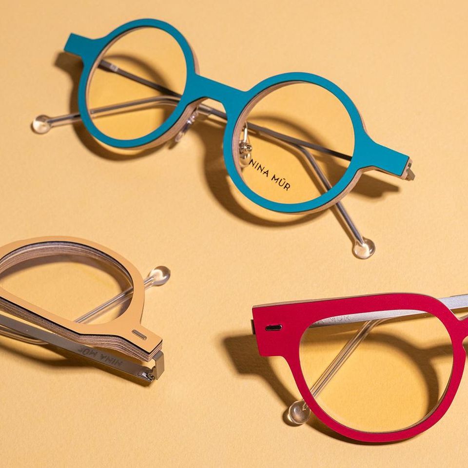 Three bright colored wood and laminate glasses are sitting on a yellow surface