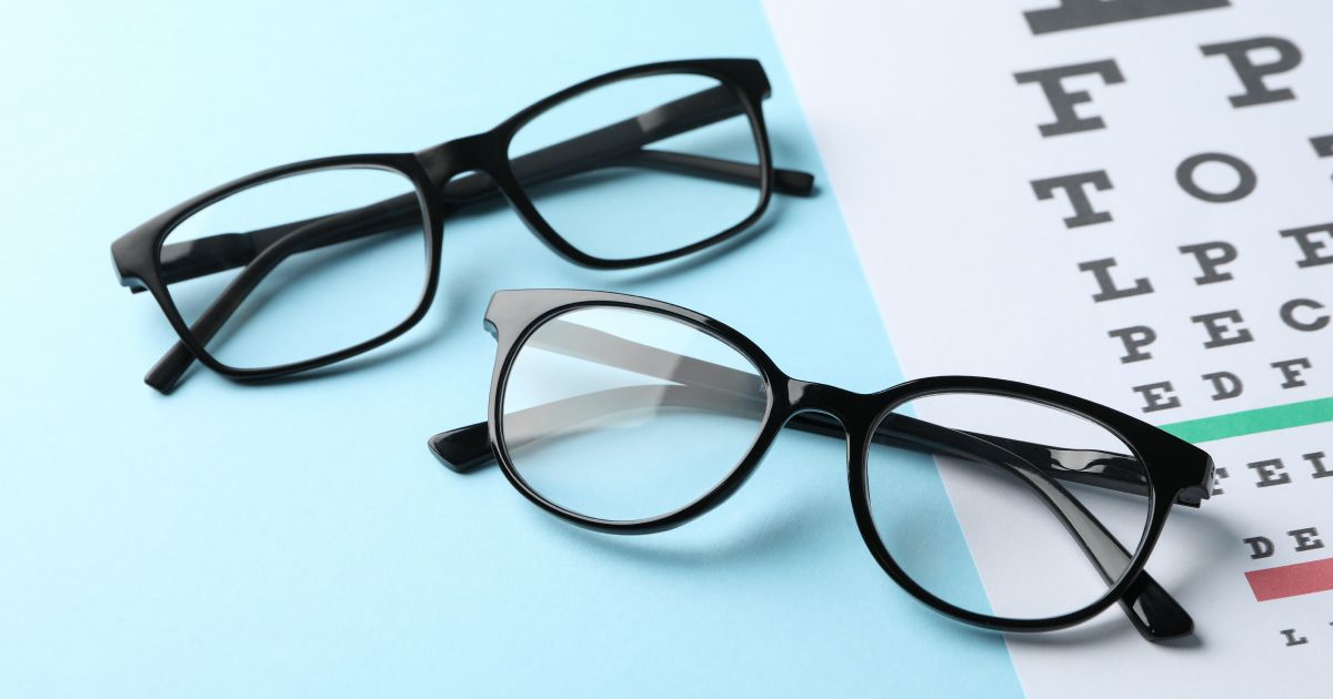 Two pairs of glasses sitting on top of an eye test chart.