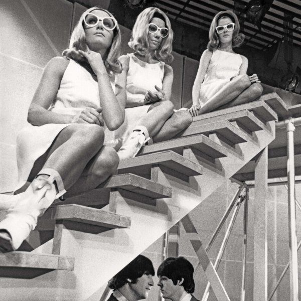 Three women from the 60's in sunglasses sitting on a staircase