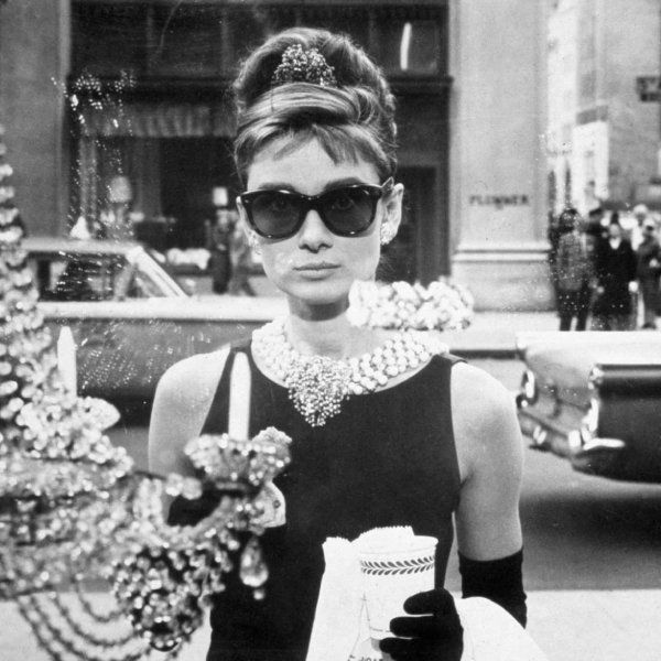 Audrey Hepburn from the movie Breakfast at Tiffany's wearing her iconic black dress, pearls and Oliver Goldsmith glasses