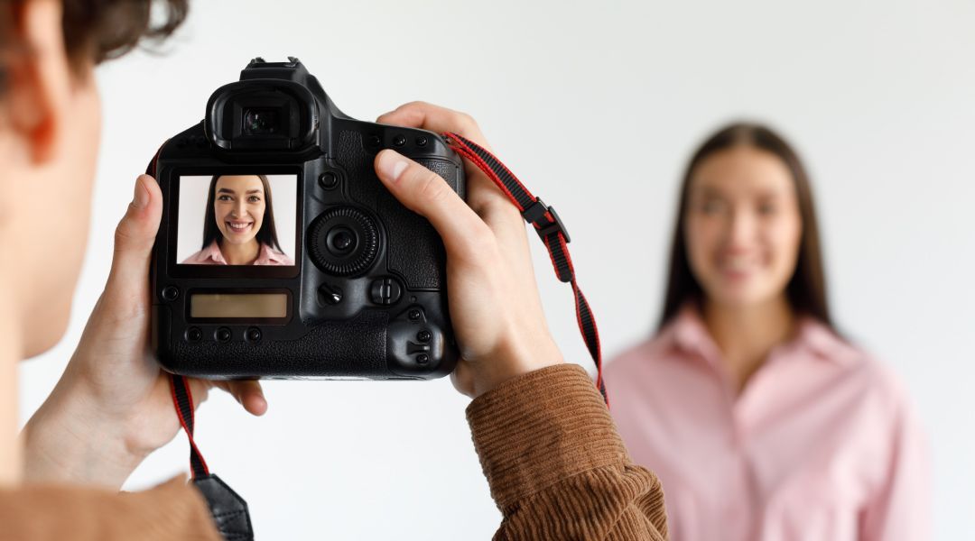 A man is taking a picture of a woman's face with a camera .