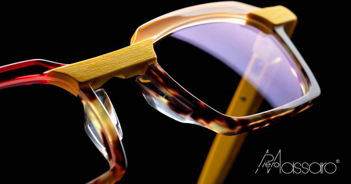 A pair of Piero Massaro glasses in red, yellow and tortoise on a black background.