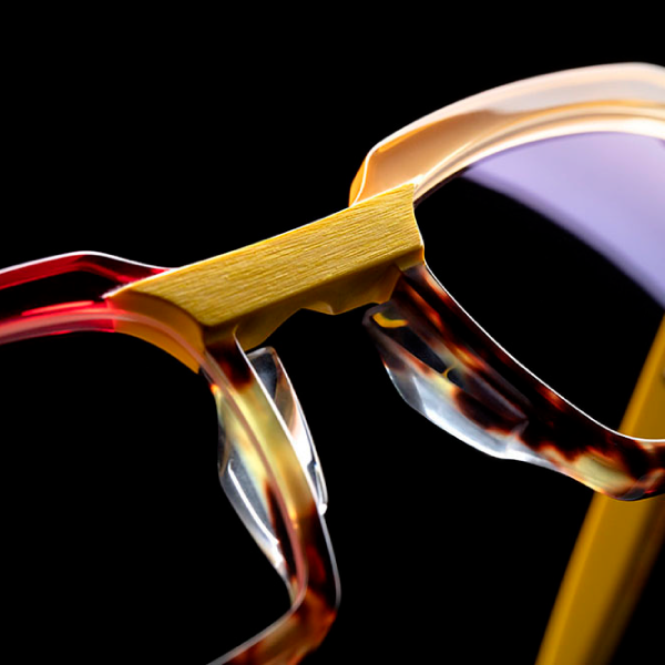 A close up of a pair of glasses in red and yellow on a black background