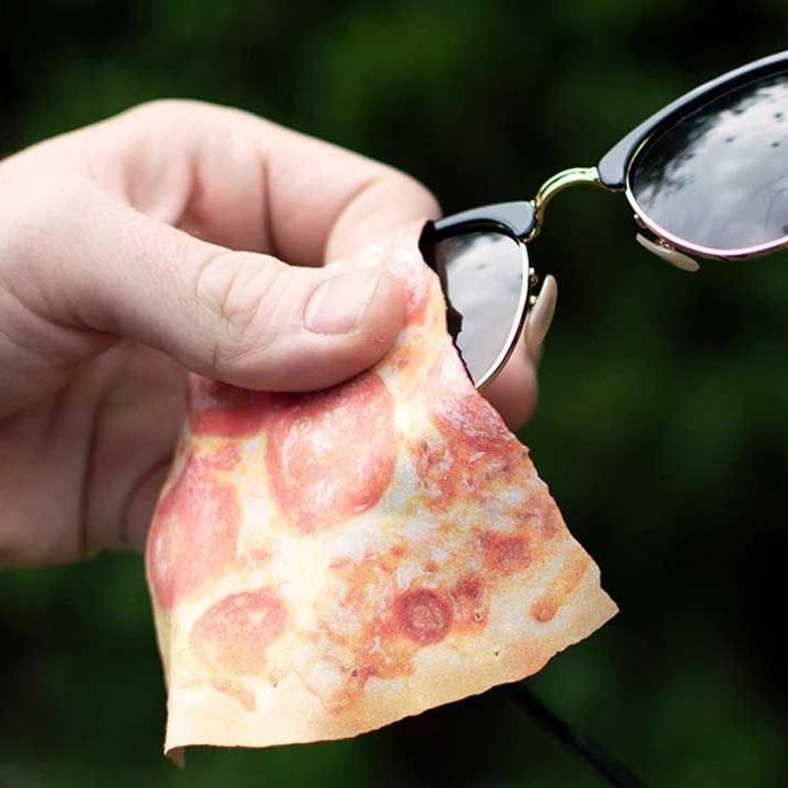 A pair of sunglasses being cleaned with a microfiber cleaning cloth printed with a slice of pepperoni pizza on it.