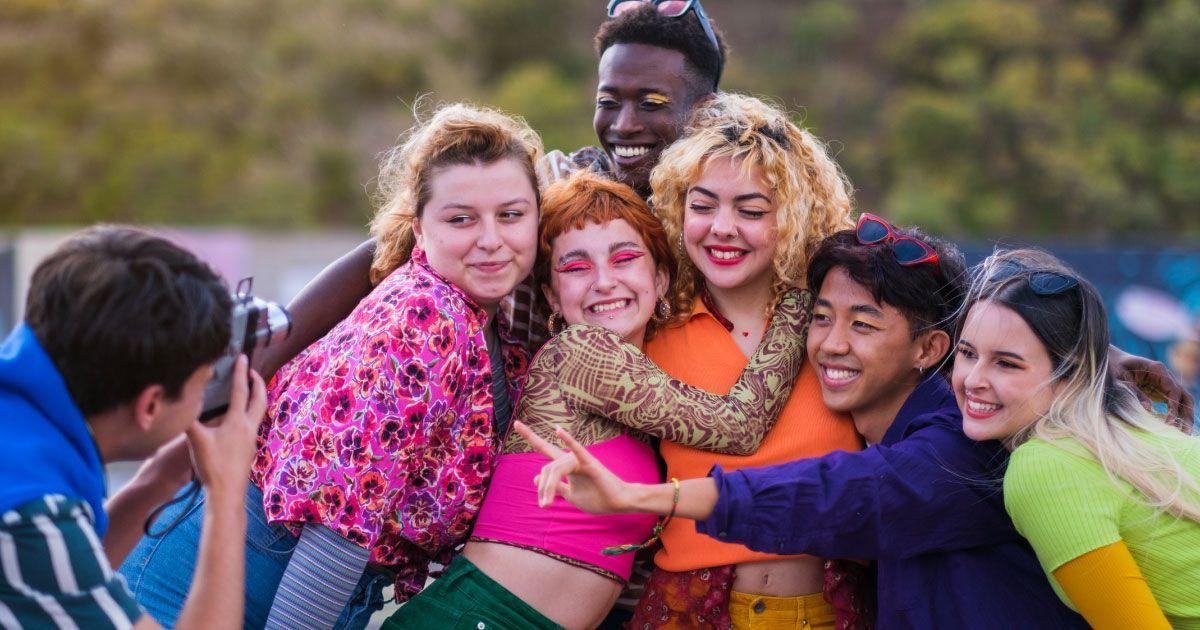 Colorfully dressed young adults posing as a photographer takes their picture.