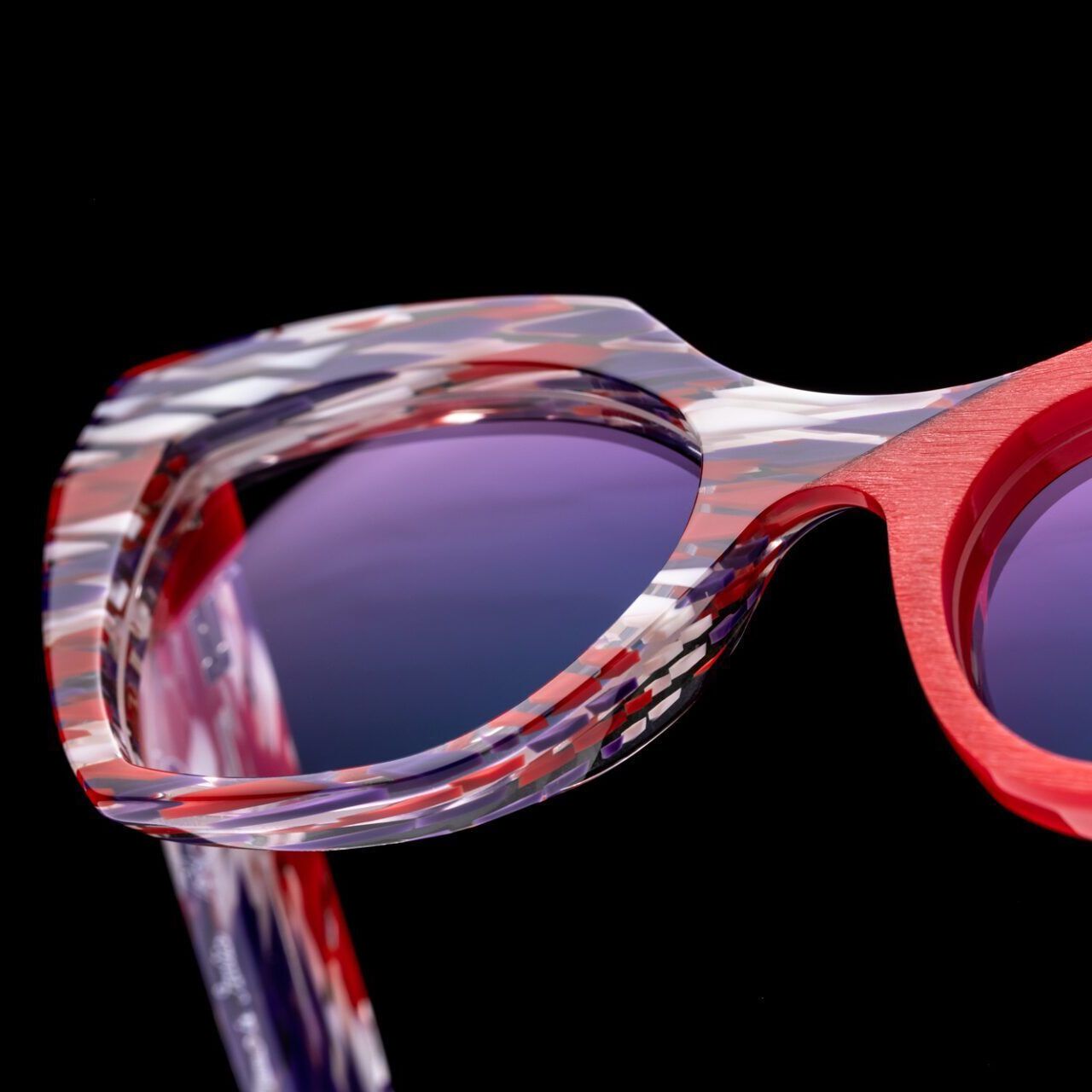 A pair of red white and purple Piero Massaro glasses on a black background