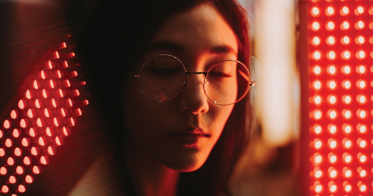 Close-up of a person with glasses in  red LED lights , looking down thoughtfully