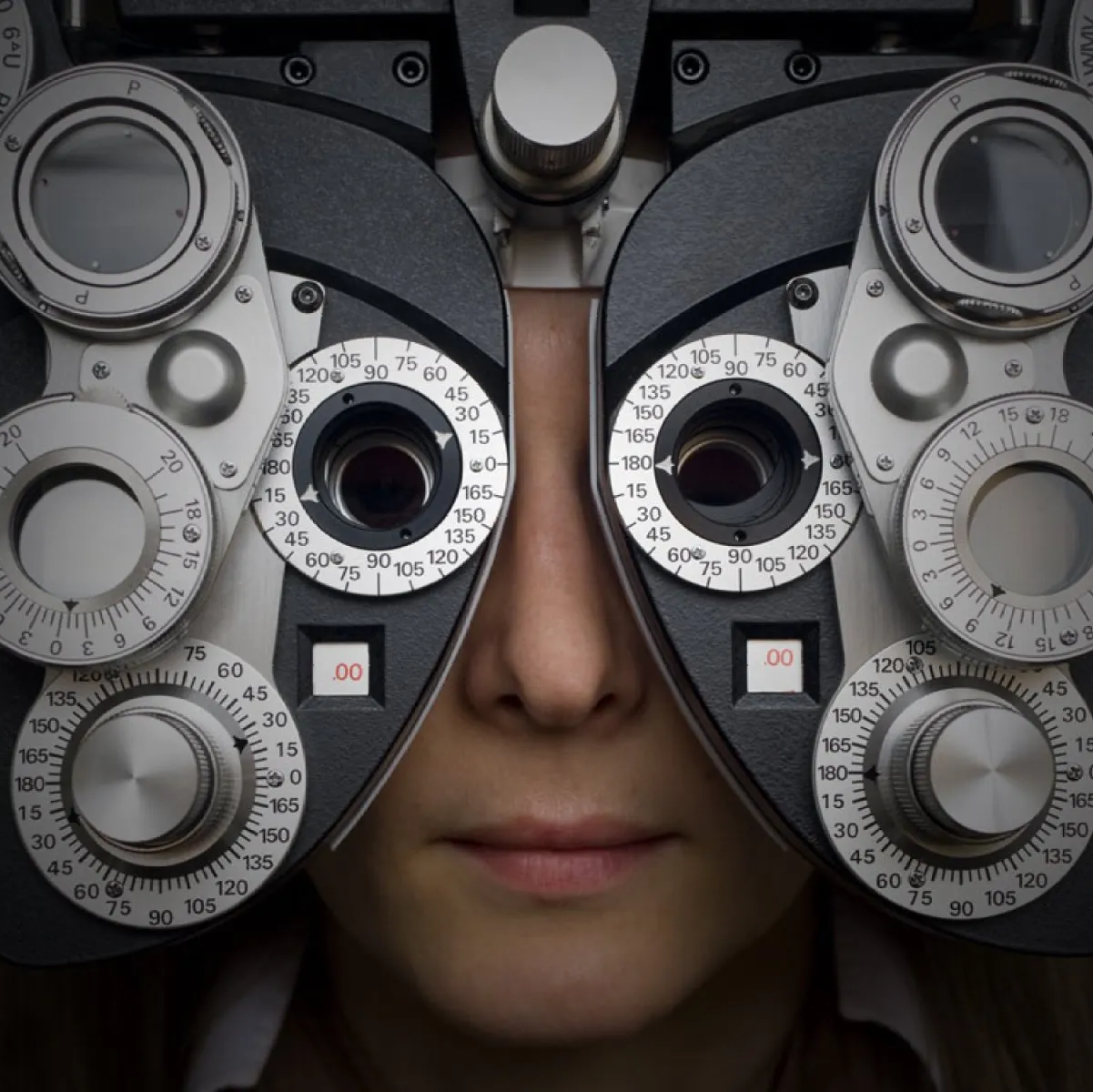 Close up of a person looking through a phoropter during an eye exam