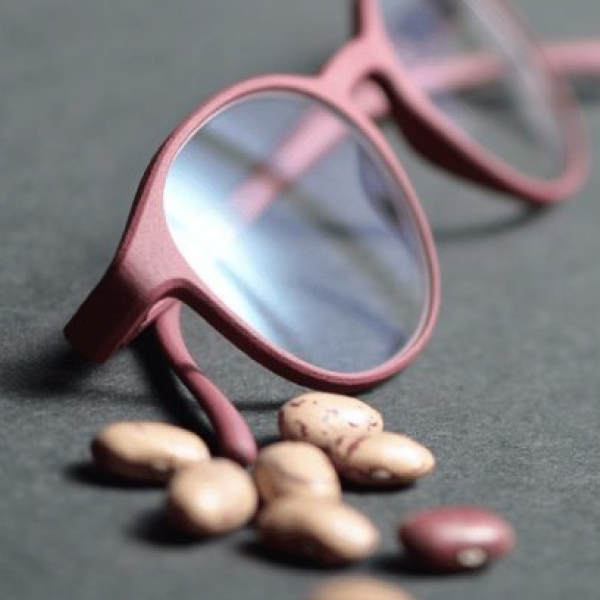 A pair of Rolf glasses laying next to a pile of beans