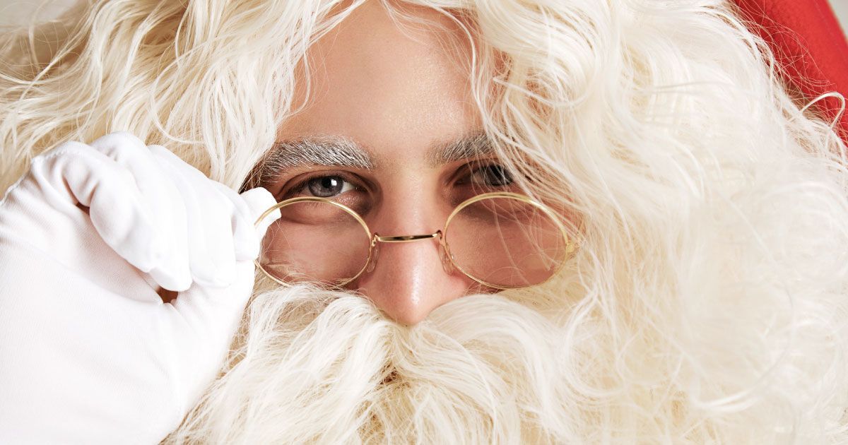 A close up of santa claus ' face with glasses and a beard.