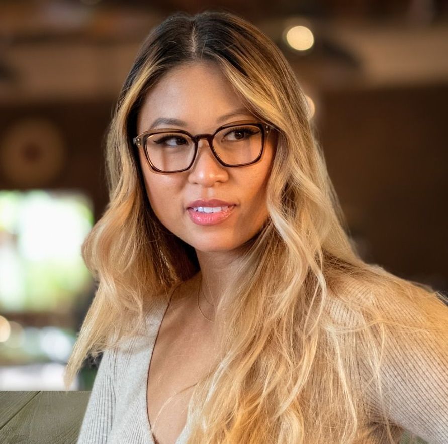 A smiling woman wearing a brown and tortoise pair of Say-oH glasses 