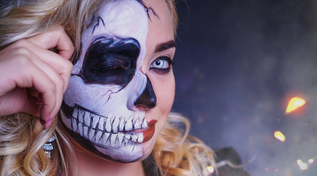Woman wearring colored contacts with a skelloton painted on half of her face