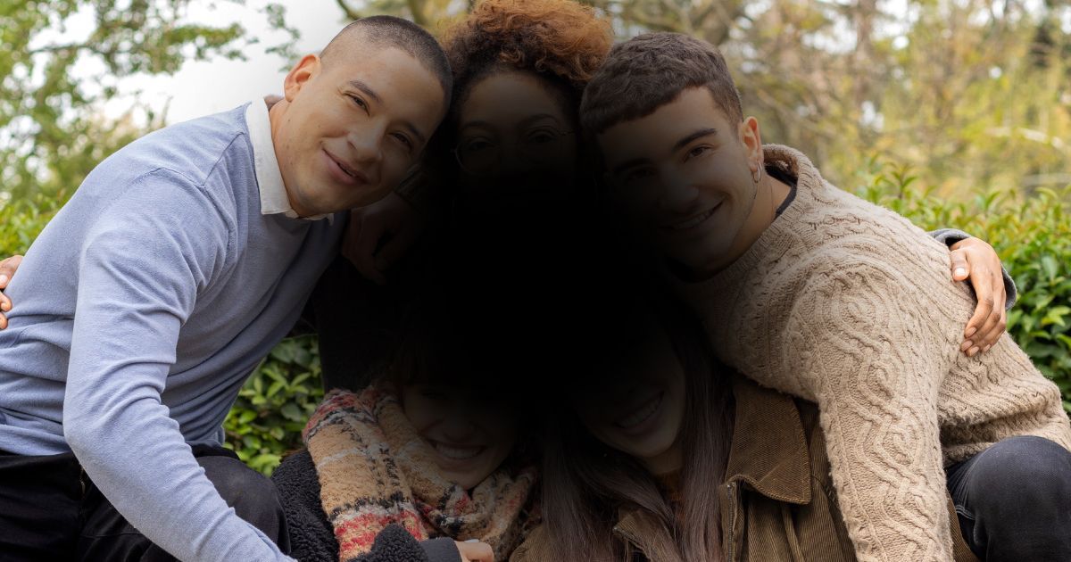 A large black spot is blurring an image of five people who are posing for a picture.