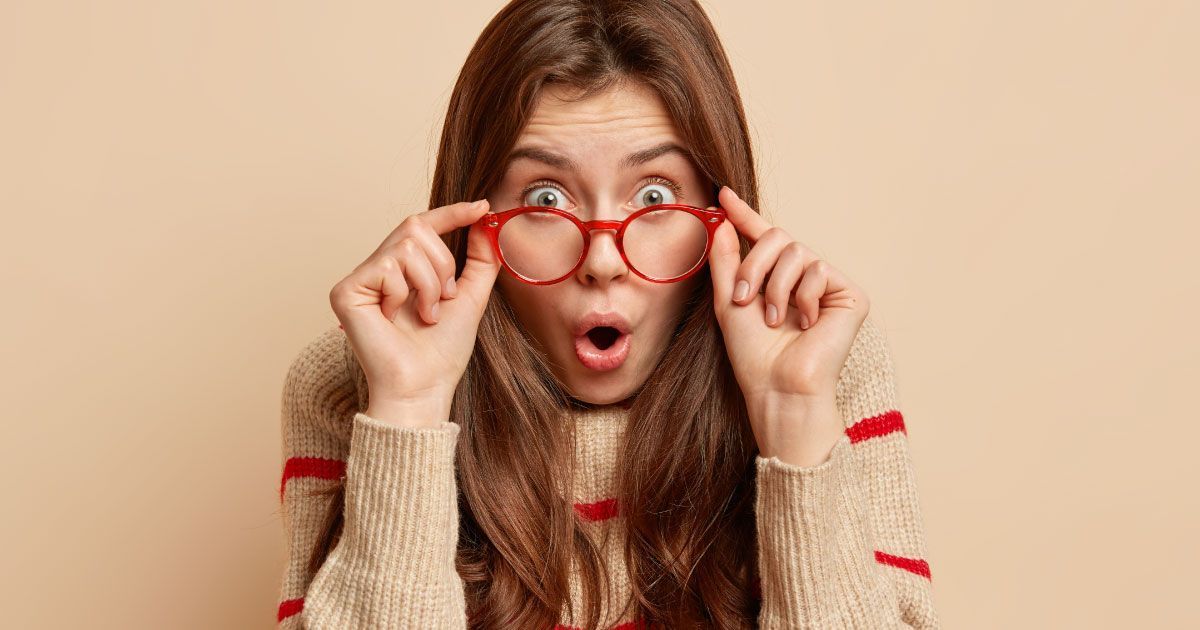 A woman wearing glasses is making a surprised face.