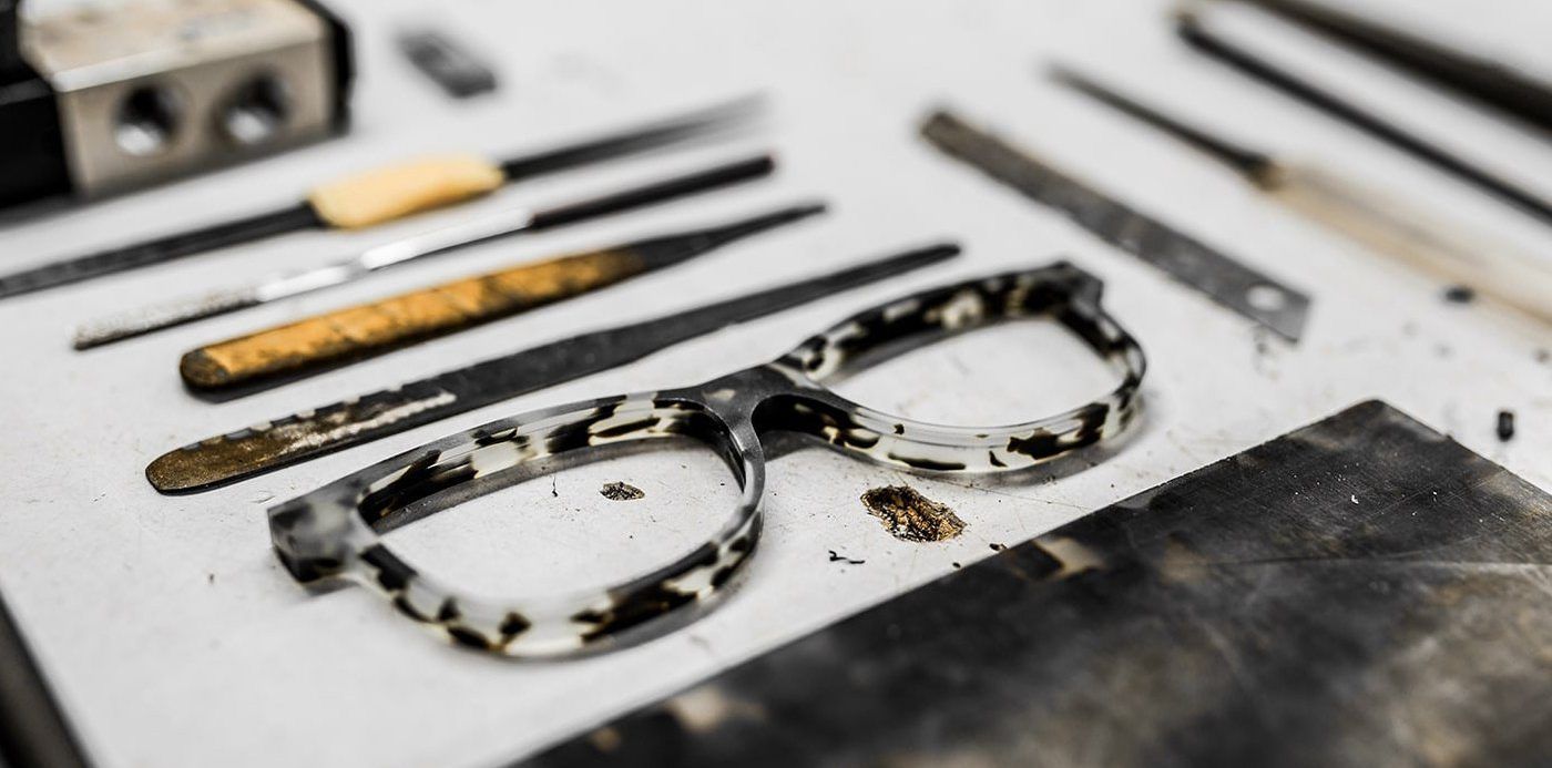 Frame face cut out of accetate with tools that are used in crafting eyewear surrounding it