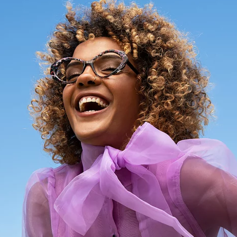 Woman in lavender blouse wearing multicolored eyeglass frames
