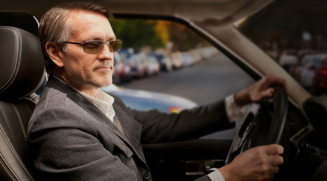 Man driving a car with darkend lenses on his glasses