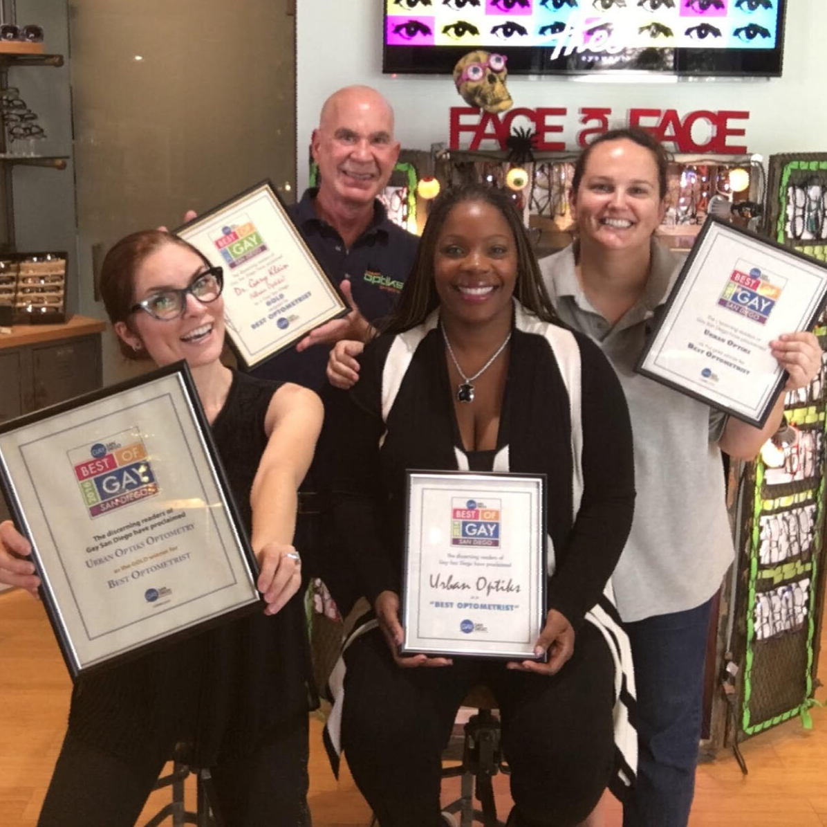 Four team members posing with four framed award certificates
