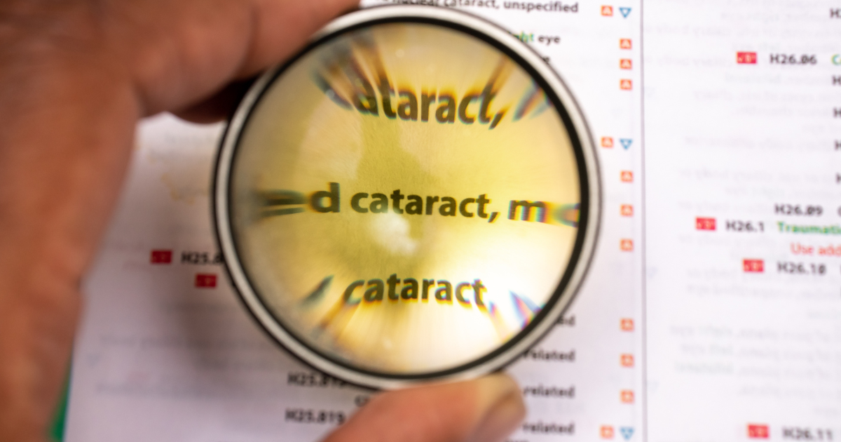 Person holding a magnifying glass over info about cataracts 
