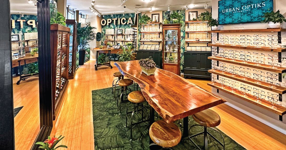 Interior phot of Urban Optiks Optometry with wooden table, green rug, shelves of eyeglass frames, an