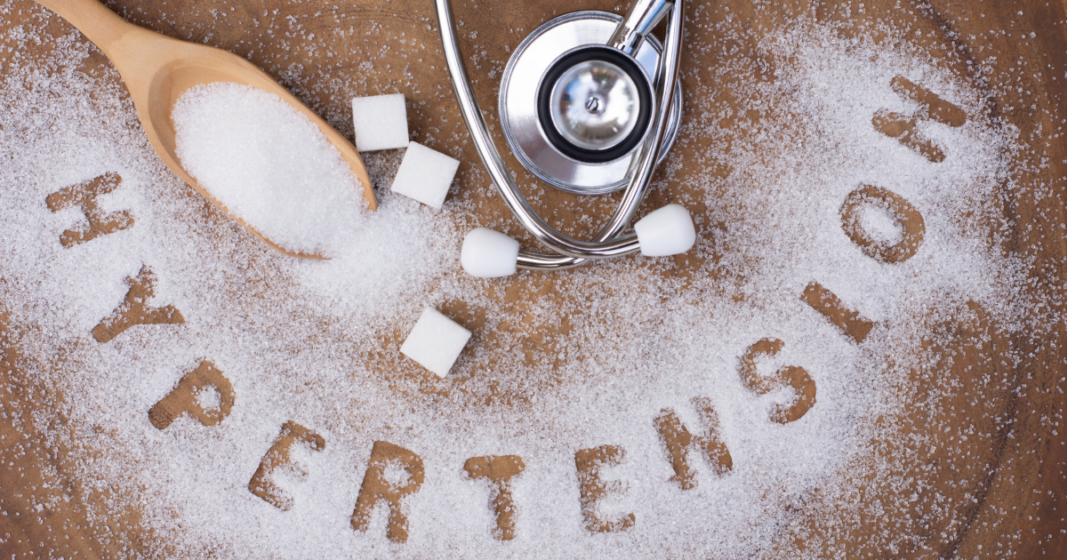 A stethoscope, wooden spoon, and the word hypertension spelled out in sugar