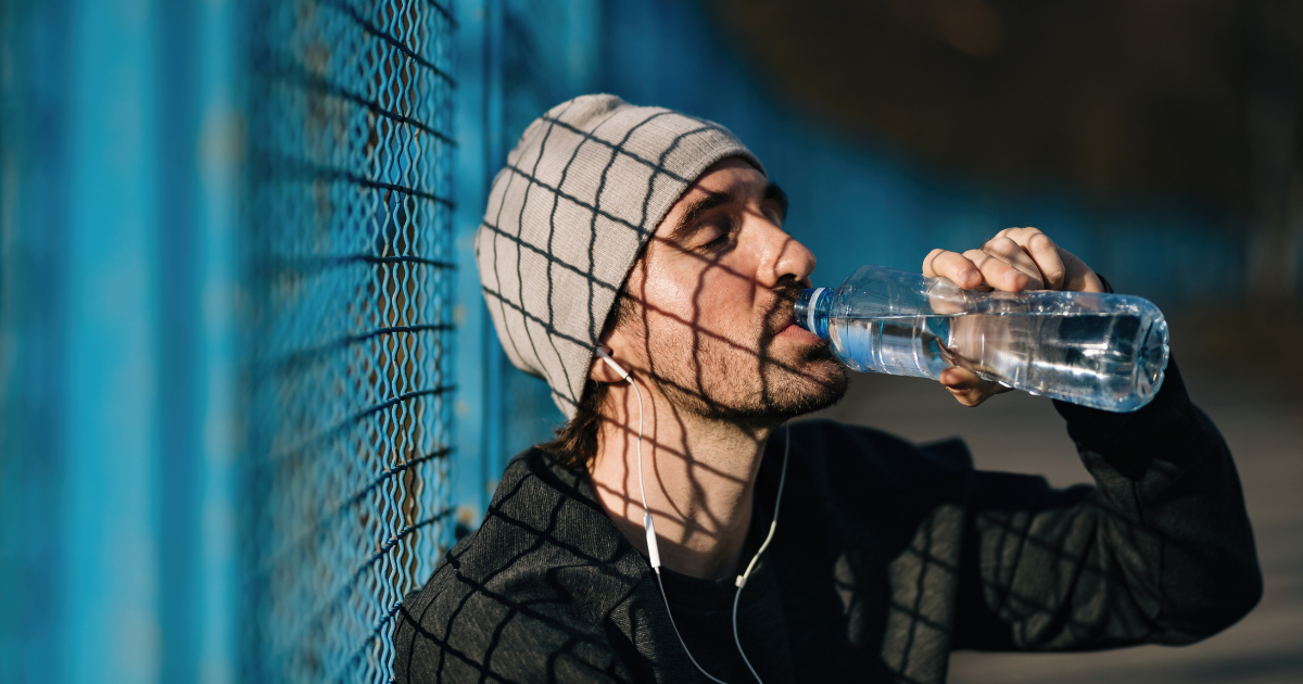 Person in cap and jacket drinking a bottle of water