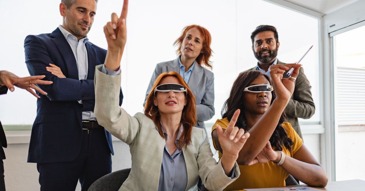 A group of people having a meeting in an office with two of them wearing virtual reality glasses.