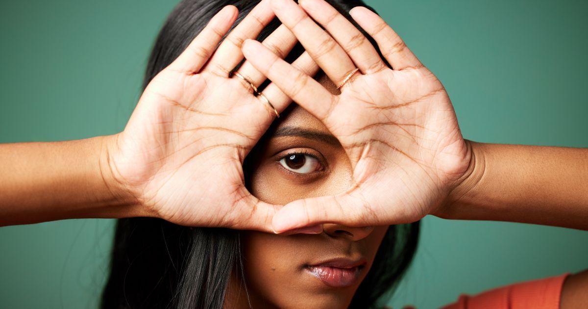 A woman holding up her hands around her eyes.