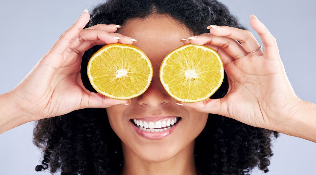A woman covering her eyes with two slices of lemon