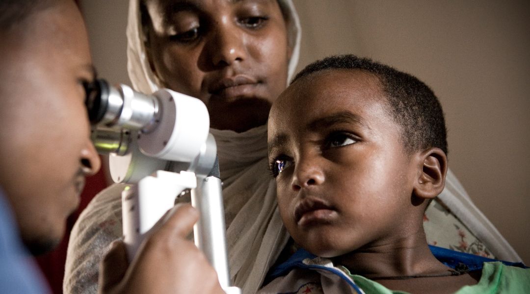A doctor is examining a child 's eye with a microscope.