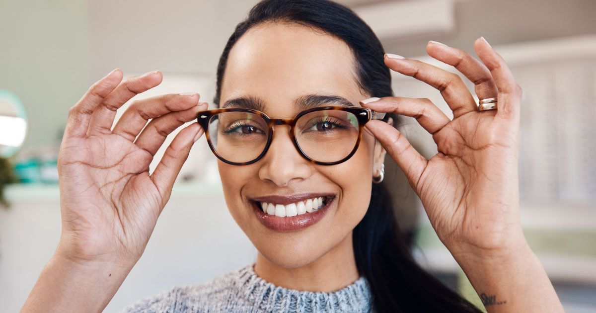 A woman is wearing glasses and smiling.